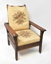 A 1930s oak adjustable open arm elbow chair with ladder back and loose tapestry-style cushions,