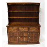 A reproduction oak dresser, the boarded plate rack with two fixed shelves above a base of three