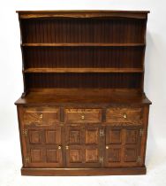 A reproduction oak dresser, the boarded plate rack with two fixed shelves above a base of three