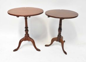 Two mahogany circular tilt-top occasional tables raised on turned columns and outswept scrolling