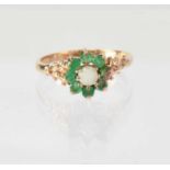 A 9ct gold cluster ring set with opal and emeralds, with stylised shoulders, stamped '375', size R
