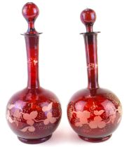 A pair of 19th century cranberry glass decanters of shaft and globe form, with etched decoration