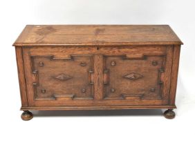 A 19th century oak coffer with applied decoration to the front, raised on bun supports, 64 x 121 x