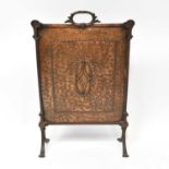 An early 20th century brass fire screen with carrying handle and central motif, on splayed feet,