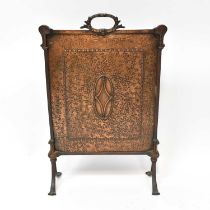 An early 20th century brass fire screen with carrying handle and central motif, on splayed feet,