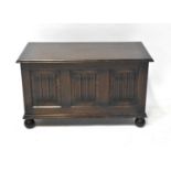 An early 20th century oak cross-banded coffer, decorated with three linenfold panels to the front,