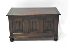 An early 20th century oak cross-banded coffer, decorated with three linenfold panels to the front,