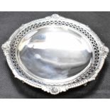 A small George V hallmarked silver circular pin dish with shell, scroll and pierced border, raised