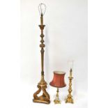 A carved gold-coloured standard lamp in the Baroque form, together with two similar table lamps (