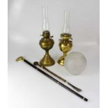 Two brass oil lamps with funnels, one with an etched shade, together with a modern walking stick