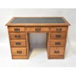 An Edwardian oak nine-drawer kneehole desk, with leather inset panel to the top, raised on plinth