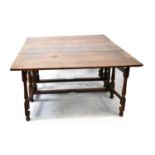 A 19th century oak gateleg drop-leaf supper table with plank top over turned block and baluster legs