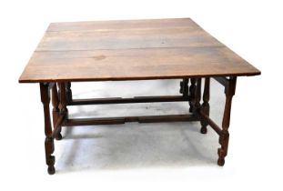 A 19th century oak gateleg drop-leaf supper table with plank top over turned block and baluster legs