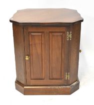 A contemporary oak freestanding cabinet, with shaped top above four panelled doors, raised on plinth