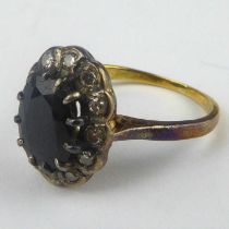 An 18ct gold sapphire and diamond ring, the marquise cut claw set sapphire in a border of tiny