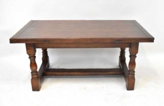 A 20th century oak refectory-style draw-leaf table, on baluster supports united by an H-stretcher,