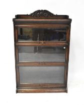 An oak three-tier glazed bookcase, with three-quarter carved galleried top above three graduated