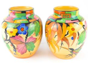 A pair of Art Deco decorated baluster vases with bright coloured geometric borders and bird and leaf