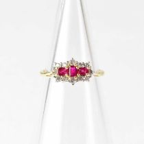 An 18ct yellow gold ring set with three rubies in a surround of diamonds, in claw settings,