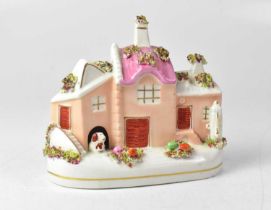 A 19th century Staffordshire model of a cottage, with spaniel and floral encrusted decoration,