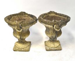 A pair of reconstituted stone urns of Classical form, with strapwork and rope-effect handles, raised