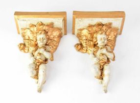 A pair of plaster wall brackets in the form of cherubs holding flowers, in a craquelure and gilt