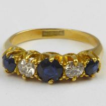 An 18ct gold diamond and sapphire ring, the central claw set brilliant cut sapphire flanked by two