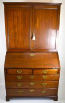 A George III oak bureau bookcase, the two-door cabinet top enclosing shelves, on fall-front bureau