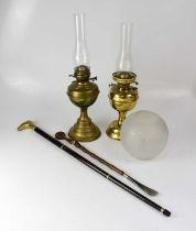 Two brass oil lamps with funnels, one with an etched shade, together with a modern walking stick