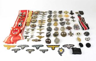 A quantity of period and later reproductions of Third Reich and SS cap badges, cloth badges,