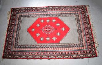 An early 20th century hand knotted red ground rug with central medallion, within a stepped geometric