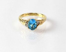 A 10ct gold ring set with topaz, with a small diamond either side to the wrythen shoulders,