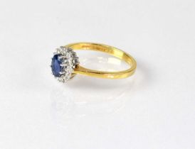 An 18ct yellow gold cluster ring, with central set sapphire in a surround of diamonds, in a white