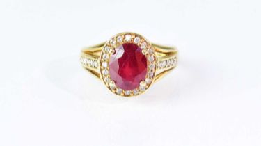 An 18ct yellow gold ring, set with central ruby in a claw mount, surrounded by small diamonds, the