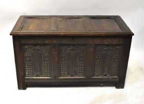 A George III oak triple-panelled coffer with later carved decoration to the front, raised on stile