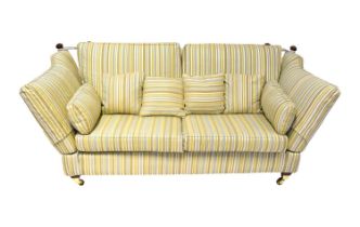 A reproduction Knoll settee with wooden finials, upholstered in a striped gold, blue, green and