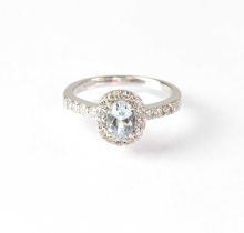 An 18ct white gold ring set with central pale blue stone, in a surround of diamonds with diamond set