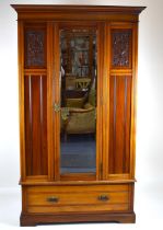 A Victorian mahogany wardrobe with single glazed door flanked by two carved panels, above a single-