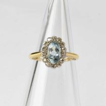 An 18ct gold cluster ring set with an aquamarine in a surround of fourteen diamonds in white gold