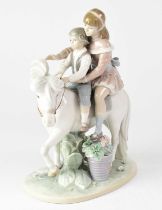 LLADRÓ; a figure group 'Pony Ride', depicting two children riding a white pony, on an oval base,