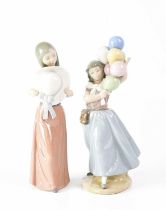 LLADRÓ; two figures of girls, one holding a wide-brimmed hat, the other holding a bunch of balloons,