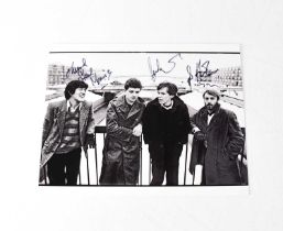 JOY DIVISION; a black and white promotional photograph signed by Peter Hook, Stephen Morris, and