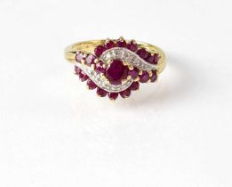 A 9ct yellow gold dress ring set with central ruby and smaller rubies, with central illusion set