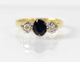 An 18ct gold ring set with a central oval sapphire, flanked by an illusion set diamond to each side,