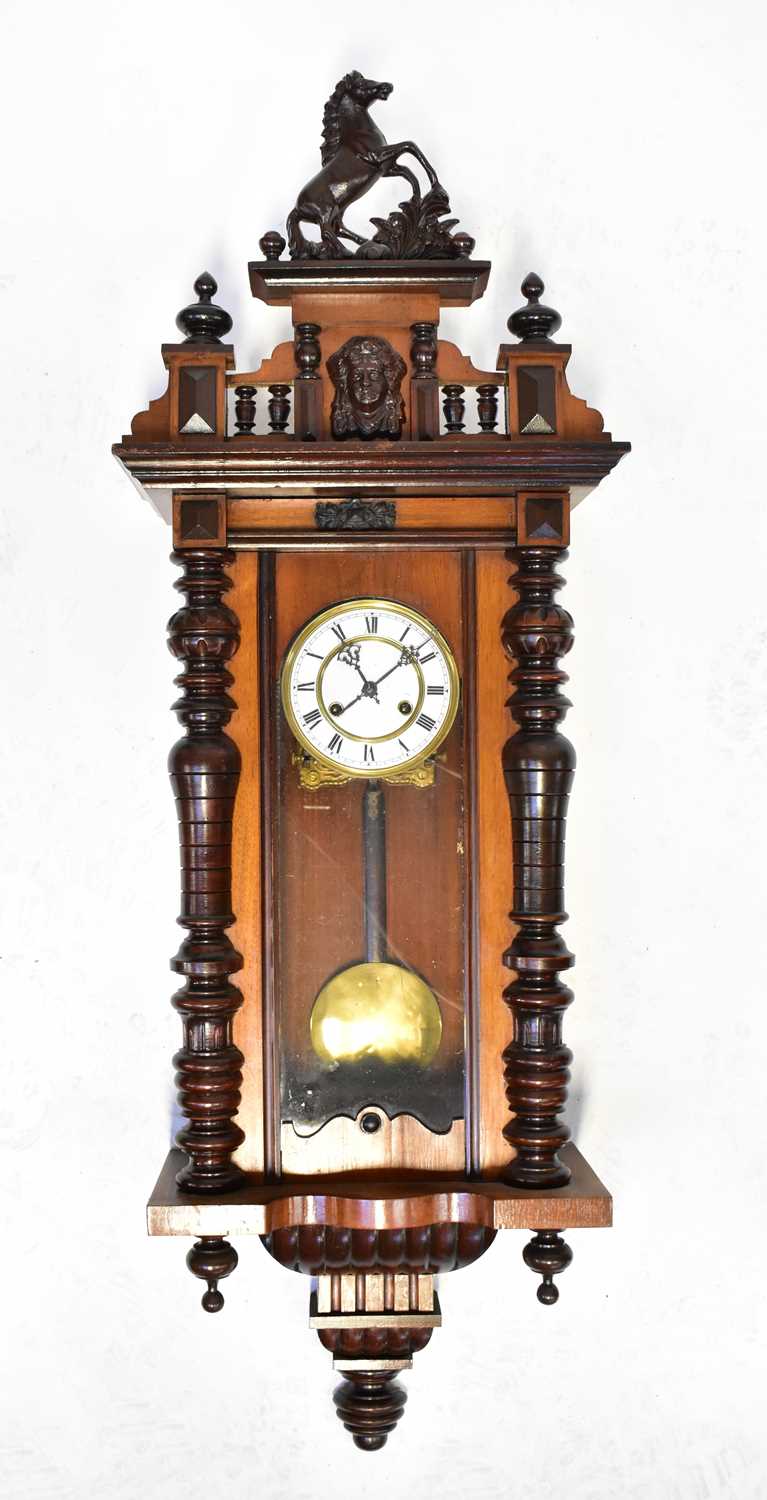 A Vienna mahogany wall clock, the pediment with a rearing horse and Classical mask, the enamelled