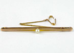 A 15ct gold bar brooch with single seed pearl centre and gold safety chain, length 5cm, approx. 2g.