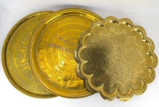 Three large Indian/Persian brass trays, one with scalloped edge and Islamic scenes and temples to