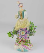 CHELSEA; a late 18th/early 19th century porcelain figure of a lady stood in front of a flowering