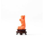 A small Chinese coral carving of a figure upon a wooden base, height of figure 3.5cm.