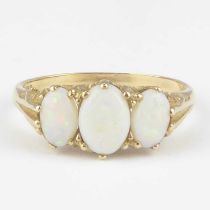 A 9ct gold opal ring, the three graduated claw set white opals with flashes of green, red and